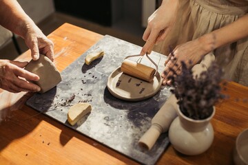 Potter using rolling pin making clay plate with lavender decoration