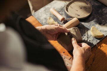 Potter decorating clay vase with lavender flowers in workshop
