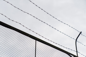 barbed wire fence on cloudy sky background symbol of security protection border prison danger...