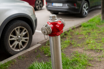 modern street fire hydrant with red metal head and stainless steel body near parked cars on urban...
