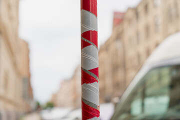 red and white striped warning tape wrapped around metal pole on urban street construction site with...
