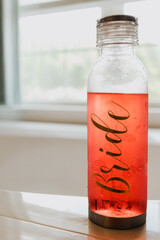 Close-up of chilled Bridle-branded pink infusion beverage in clear glass bottle with condensation...