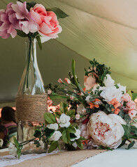 Rustic burlap-wrapped glass bottle vase with pink peony, rose, hydrangea and eucalyptus arrangement...