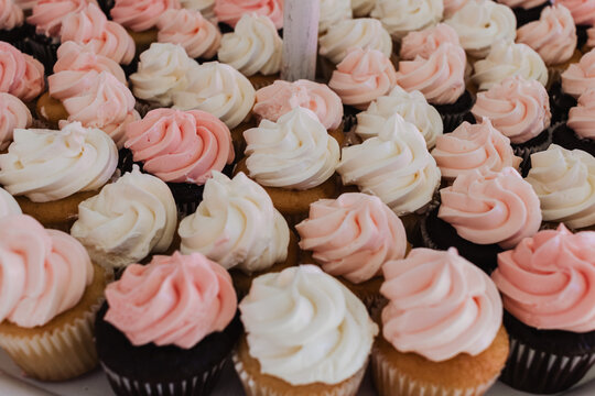 Assorted pink and white frosted vanilla and chocolate cupcakes arranged in a dessert buffet display