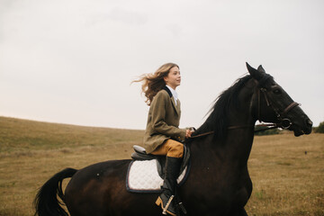 Young Woman Riding a Black Horse in a Scenic Open Field