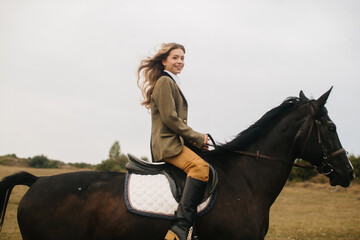 Woman Riding a Black Horse Through an Open Field in Autumn