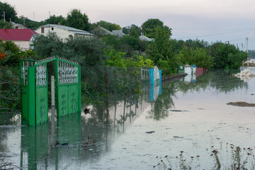 Green Gate and Fences Submerged in Flooded Village Scene | Rural Community Facing High Waters