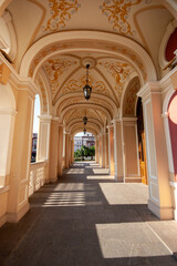 An elegant arched hallway with ornate gold and cream ceiling decorations and hanging lanterns,...