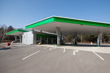 Modern, clean gas station with multiple fuel pumps and convenience store entrance, ideal for themes of travel, transportation, and energy infrastructure © Bolucevschi