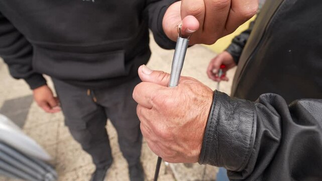 Professional technicians testing flexible spring device during maintenance work on urban street in South America, demonstrating collaborative problem solving and mechanical expertise