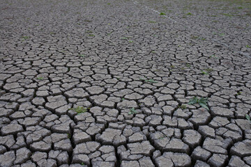 Abandoned fishing net draped over severely cracked, dry lakebed or riverbed, symbolizing drought,...