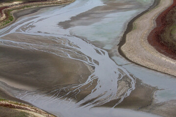 Aerial View of Dried Riverbed or Lakebed with Minimal Water and Exposed Sand Patterns, Illustrating...