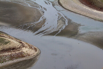 Aerial View of Dried Riverbed or Lakebed with Minimal Water and Exposed Sand Patterns, Illustrating...