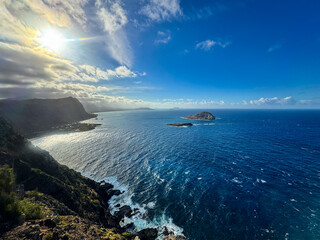 Stunning aerial view of Rabbit Island from Makapuʻu Lighthouse, Oahu—turquoise Pacific waves crash along the dramatic volcanic coastline under a vibrant Hawaiian sky.
