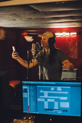 Singer recording song using smartphone in professional studio