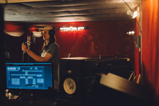 Singer recording song in professional studio with microphone