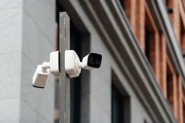 white video camera attached to wall of apartment building for outdoor surveillance