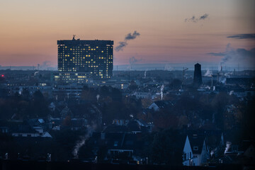 Cologne City skyline at dawn with large glowing city buildings and a twilight sky.