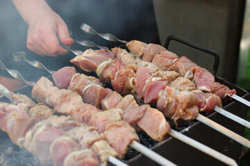 Fresh meat on a metal skewer in a man's hand. Fresh meat cooked at barbecue. BBQ fresh beef meat...