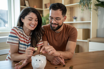 Happy couple saving money together in piggy bank at home