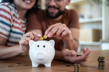 Happy couple saving money together in piggy bank