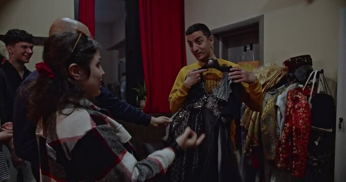 Actors backstage in dressing room discuss costume choices and laugh together before a theatre play.