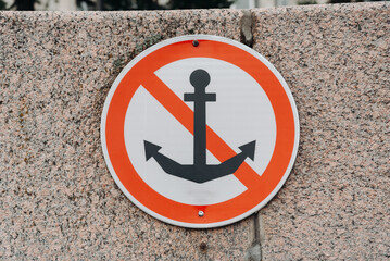 forbidding marine navigation sign, do not drop anchors, attached to stone embankment
