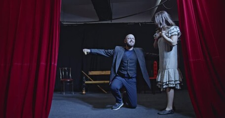 Two actors rehearse a dramatic scene on a theater stage. They practice their lines and movements with passion and intensity.