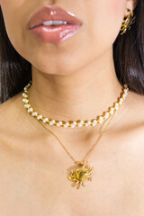 An unrecognizable woman modeling a beautiful gold necklace she's wearing around her neck inside a...