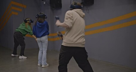 Friends enjoy virtual reality gaming together. They wear VR headsets and hold controllers, immersed in a digital world.