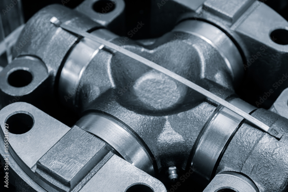 Poster close up of a metal piece with a silver band wrapped around it. the piece is a part of a machine and