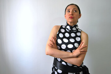 beautiful young latina woman with polka dot dress crossing arms with serious expression