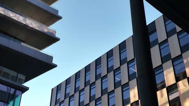Modern urban architecture in Vilnius featuring intersecting buildings with reflective glass and metallic panel exteriors under clear sky.