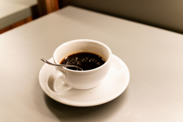 White coffee cup with spoon on light background. Morning cappuccino made by professional barista. Drawings on surface of coffee drinks. Flatlay with hot drinks. 