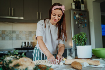 Young caucasian woman making bread dough with rolling pin and flour	
