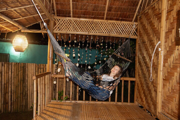 Vacation in Thailand in bugalow. Sea, beach, tropical fruits and drinks. Fit couple in hammock.