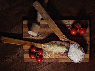 Rustic still life with rice, tomatoes and wooden spoons