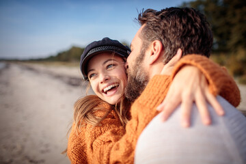 Romantic couple walking on the beach in cozy autumn sweaters