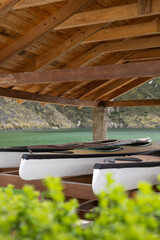 Tucked beneath a rustic roof, a group of kayaks rests silently by the lake. The scene speaks of...