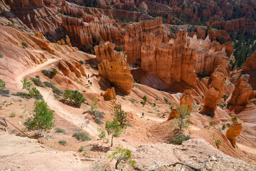 View from canyon rim of rock hoodoos and people on the queens loop hiking trail, summer vacation exploring in Bryce Canyon National Park, Utah
