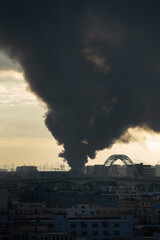a distant towns building on fire in the early morning emitting thick black smoke at vertical composition