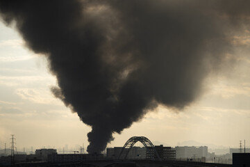 a distant towns building on fire in the early morning, emitting thick black smoke
