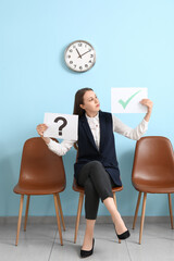 Female applicant holding paper sheets with question and check marks in room