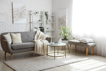 Interior of light living room with cozy grey sofa and coffee table