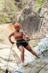Latin american female canyoneer rappelling down a rocky waterfall, demonstrating skill and courage...