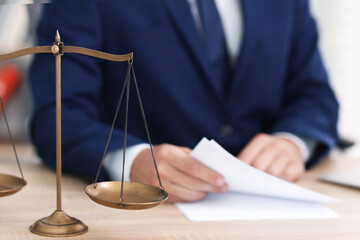 Judge working and scales on desk indoors, selective focus