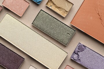 Beautiful eyeshadow refill pans on beige background, flat lay