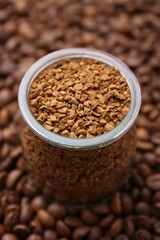 Glass jar with granulated instant coffee on beans, closeup