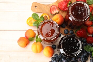 Different jams in jars and ingredients on white wooden table, flat lay
