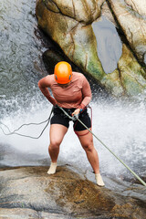 Female canyoneer skillfully descending a waterfall, showcasing courage and athleticism in the...